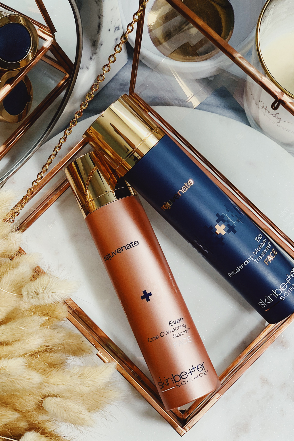 SkinBetter Science Even Tone Correcting Serum and Trio Rebalancing Moisture Treatment displayed on a marble surface with gold accents.