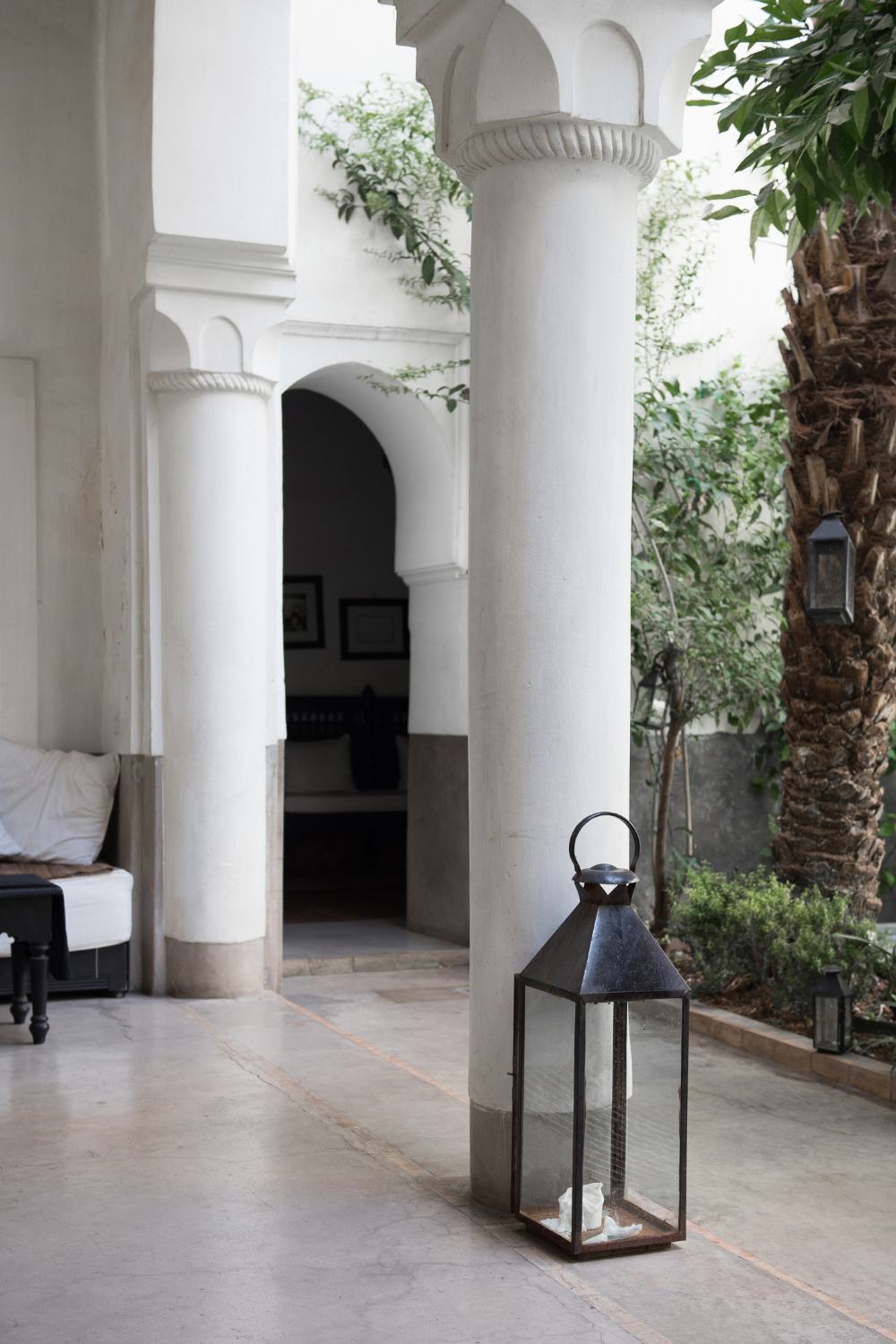 A peaceful courtyard with white columns, a lantern, and greenery, creating a serene atmosphere at Liv Med Spa.